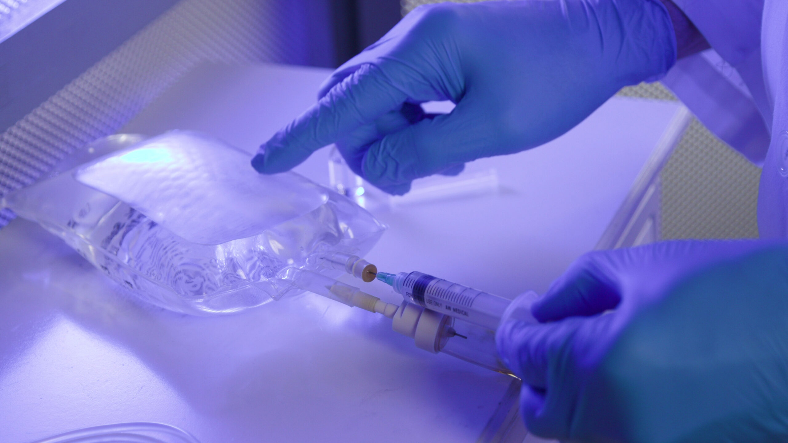 Doctor Removing Drug From IV Bag On A Table